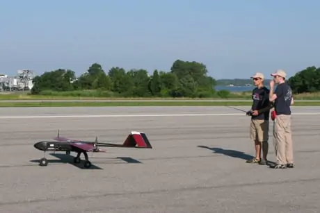 A safety pilot and spotter prepare the CUAir plane for takeoff. The remote controller is only for takeoff and landing; otherwise the plane flies autonomously. The controller can also be used to take back control of the plane if it is acting unsafely.