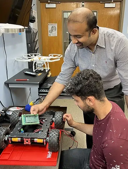 Sai Sanker assists student working on UGV in new robotics lab.